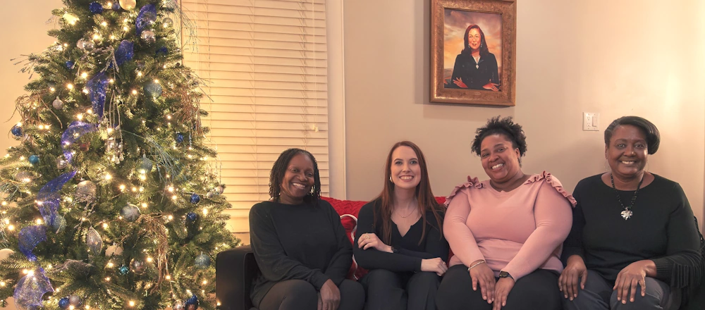Loisann’s Hope House staff sitting on a couch next to a Christmas tree.